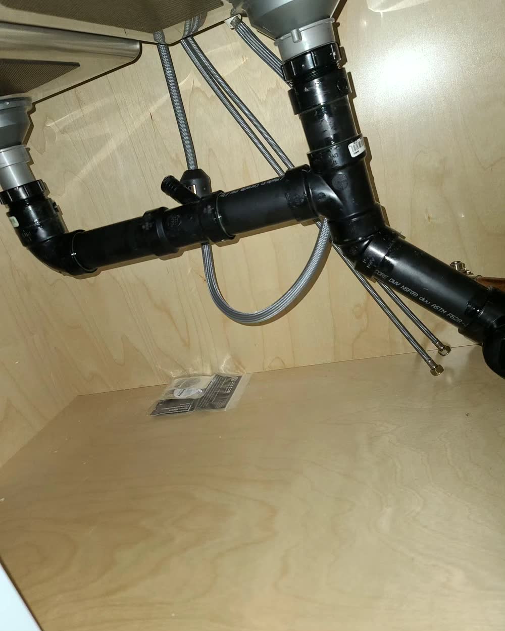New black ABS drain and trap under a kitchen sink
